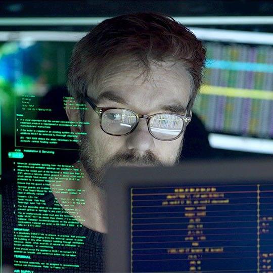 戴眼镜的男子看着各种屏幕上的电脑信息