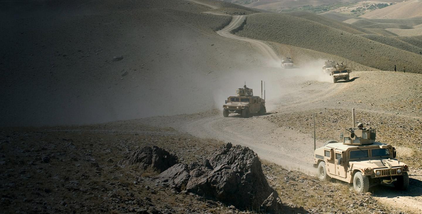 Five HUMVEEs driving on a dirt road